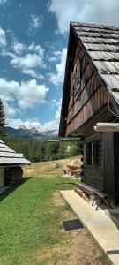 un edificio de madera con un banco delante de él en Planinska hišica pod macesni - Bohinj, en Srednja Vas v Bohinju