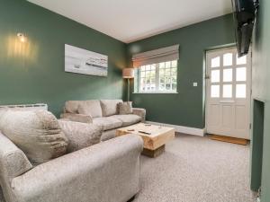 a living room with green walls and a couch and a table at Wood Cottage in Lynton