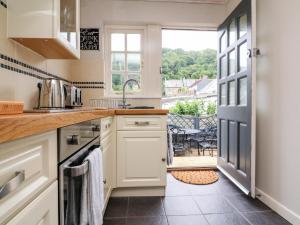 a kitchen with white cabinets and a view of a patio at Wood Cottage in Lynton