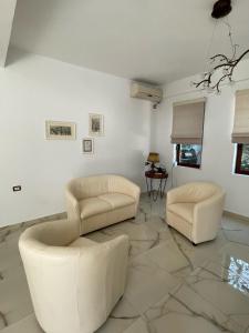 ein Wohnzimmer mit 2 weißen Sofas und einem Tisch in der Unterkunft Xho's Forest Guest House in Berat