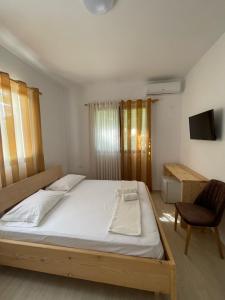 a bedroom with a bed and a chair and a television at Xho's Forest Guest House in Berat