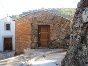 un edificio de piedra con una puerta de madera junto a una pared en Casa Capela - Casas do Sinhel, en Alvares
