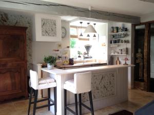 a kitchen with a sink and two bar stools at Val du Lys in Sainte-Maure-de-Peyriac