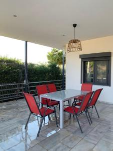 un patio con mesa y sillas rojas en Villa sun gold Lagonisi en Áyios Nikólaos