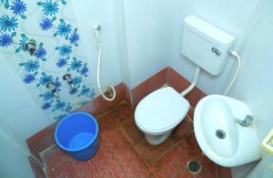 a bathroom with a toilet and a bucket in it at Hotel New West Tower in Madurai