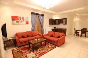 una sala de estar con 2 sofás naranjas y una mesa. en Towlan Hotel Suites 1, en Riad