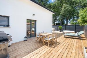 eine Terrasse mit einem Tisch und Stühlen auf einer Holzterrasse in der Unterkunft CASA MAMALOSA & SPA in Andernos-les-Bains