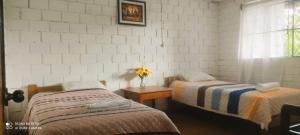 un dormitorio con 2 camas y una mesa con un jarrón de flores en Selva Mayo, en Moyobamba