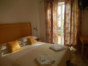 a bedroom with a bed with yellow pillows and a window at Hotel Europa in Ischia