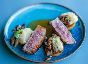 a blue plate of food with meat and mushrooms at InterContinental Cascais-Estoril by IHG in Estoril
