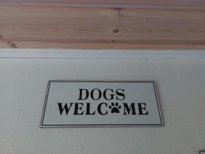 Una señal que dice que los perros me dan la bienvenida en una pared en KRAGKAER Deer-Lodge B&B A unique holiday home, en Saeby