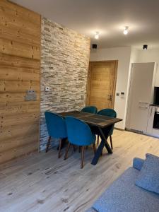 une salle à manger avec une table en bois et des chaises bleues dans l'établissement CARLINA 105, à Morzine