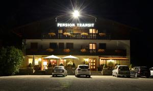 a building with cars parked in a parking lot at night at Garni Transit B&B - Your Stopover in Vipiteno