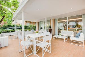 un comedor con sillas y mesas blancas en BeYou Hotel Polo, en Riccione