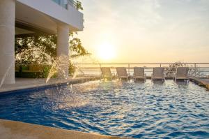 a swimming pool with chairs and the ocean in the background at Hotel Santorini Casablanca in Santa Marta