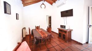 een eetkamer met een tafel en een tv aan de muur bij La Candida departamentos in Merlo