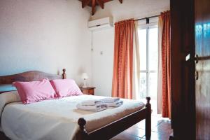 een slaapkamer met een bed met roze kussens en een raam bij La Candida departamentos in Merlo