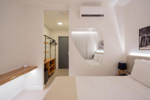 a bedroom with a white bed and a mirror at Pauli Boutique Hotel in Fortaleza