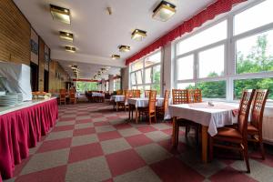 a dining room with tables and chairs and windows at Hotel Sasanka in Tatranská Lomnica