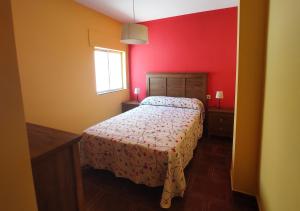 een slaapkamer met een bed en een rode muur bij Alojamiento turístico Ana María in Torreperogil