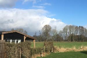 une ancienne grange dans un champ à côté d'une clôture dans l'établissement Chalet Op de Brusse, à De Heurne