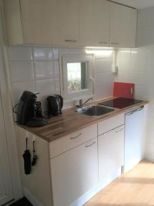 una pequeña cocina con lavabo y espejo en Chalet Op de Brusse, en De Heurne