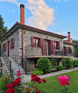 a stone house with red windows and a balcony at Φιλοξένια Studios in Vitina
