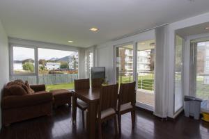 een woonkamer met een tafel, een bank en ramen bij Gray Fox Apartments Pipo in Ushuaia