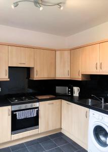 a kitchen with wooden cabinets and a washing machine at Light & Spacious Loch Lomond Apartment in Alexandria