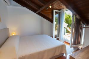 - une chambre avec un lit blanc et un balcon dans l'établissement Eleni's Guesthouse, à Paleokastritsa