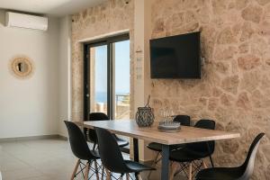 a dining room with a wooden table and chairs at Petradi Villas Skala in Skala
