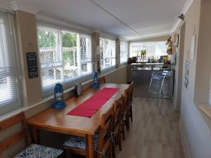 a dining room with a long wooden table and windows at Beach House with DSTV & WIFI & basic housekeeping in Knysna