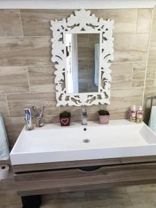 ein Badezimmer mit einem weißen Waschbecken und einem Spiegel in der Unterkunft Beach House with DSTV & WIFI & basic housekeeping in Knysna