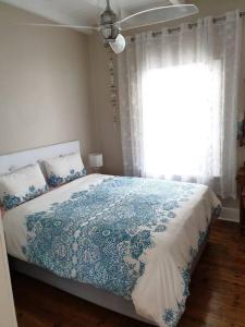 a bedroom with a blue and white bed with a window at Beach House with DSTV & WIFI & basic housekeeping in Knysna