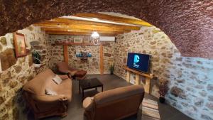 sala de estar con sofá y TV en una pared de piedra. en Lisko Vacation house en Tribalj