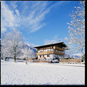 een groot gebouw met sneeuw op de grond voor de deur bij Pension Kristall in Bramberg am Wildkogel