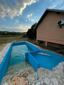 una piscina blu con un edificio di Casa Madre Kravice Waterfalls a Ljubuški