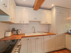 Una cocina con gabinetes blancos y un fregadero. en Greenham Rise, en Chiselborough