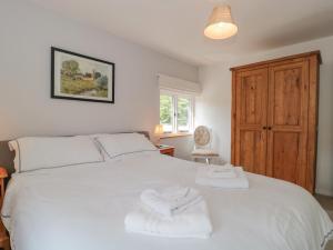 Un dormitorio con una cama blanca con toallas. en Greenham Rise, en Chiselborough