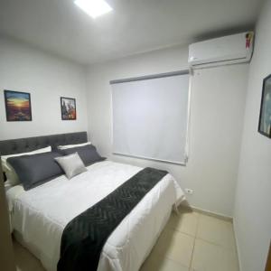 una camera da letto con un grande letto bianco e una finestra di Gran Studium a Maringá
