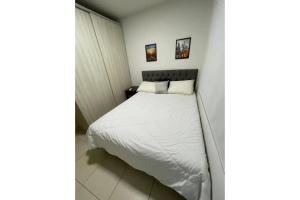 een kleine slaapkamer met een bed met witte lakens bij Gran Studium in Maringá