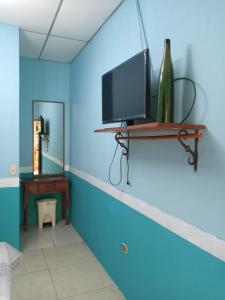 Habitación con pared azul y estante con TV. en Hospedaje Hefziba en Moyogalpa