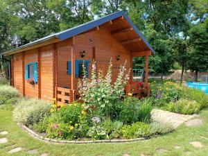 a log cabin with a flower garden in front of it at Smocze Ranczo in Ośno Lubuskie