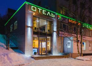 ムルマンスクにあるミニ ホテル ルームズ＆ブレックファーストの緑色のネオンの看板が貼られた建物