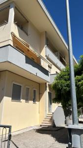 un bâtiment jaune avec des escaliers en face de celui-ci dans l'établissement Appartamento di design a 30 metri dal mare, à Alba Adriatica