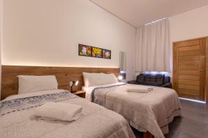 una camera d'albergo con due letti e una sedia di BH Studios Hotel Brás a San Paolo
