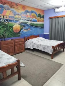 Habitación con 2 camas y una pintura en la pared. en Hospedaje Hefziba en Moyogalpa