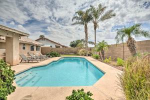 a swimming pool in a yard with chairs and palm trees at Sunny Yuma Retreat with Private Pool and Grill! in Yuma