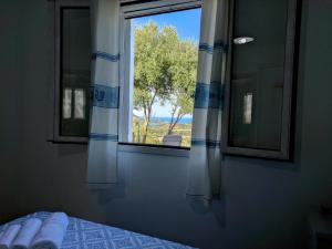 a bedroom with a window with a view of a tree at Appartamento La Ginestra - Affitti Brevi Italia in Tertenìa
