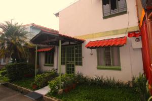 a white house with green windows and a red roof at F&M Guesthouse in San José